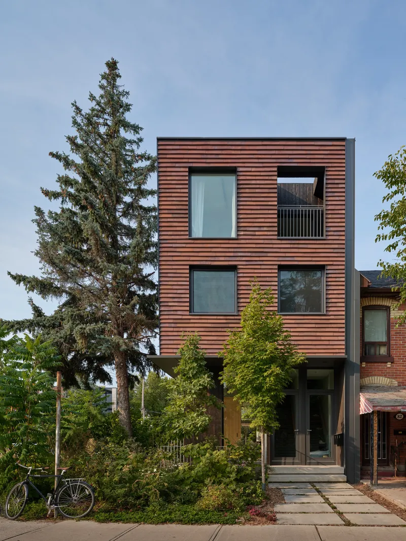 Street elevation showing the three-storey copper clad volume with paired windows and entry path