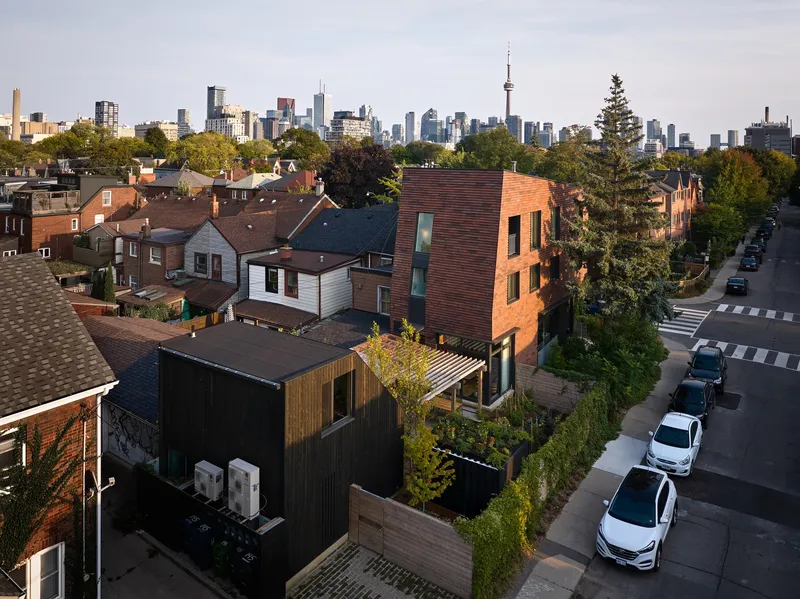 Aerial view of the terracotta brick facade rising above the residential street in afternoon light