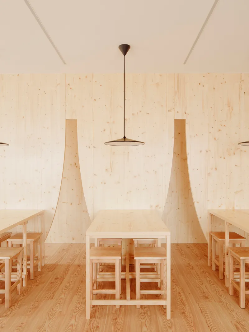 Central dining table flanked by tapered plywood wall fins under a flat disc pendant