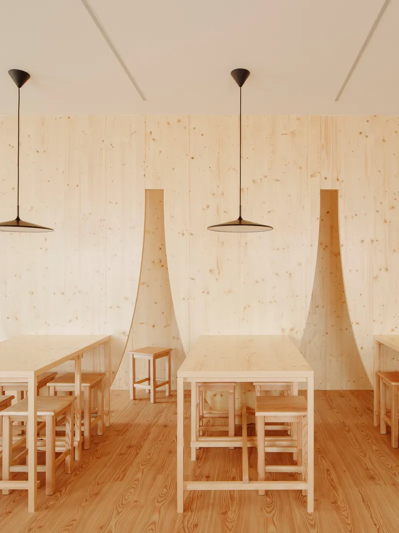 Dining table with benches framed by triangular timber dividers under pendant lights against plywood wall cladding