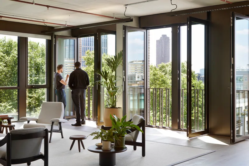Full-height folding glass doors opening onto a balcony with two residents and potted plants