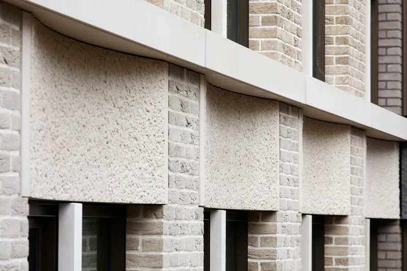 Close-up of precast concrete lintels and spandrel panels alternating with pale brick coursing
