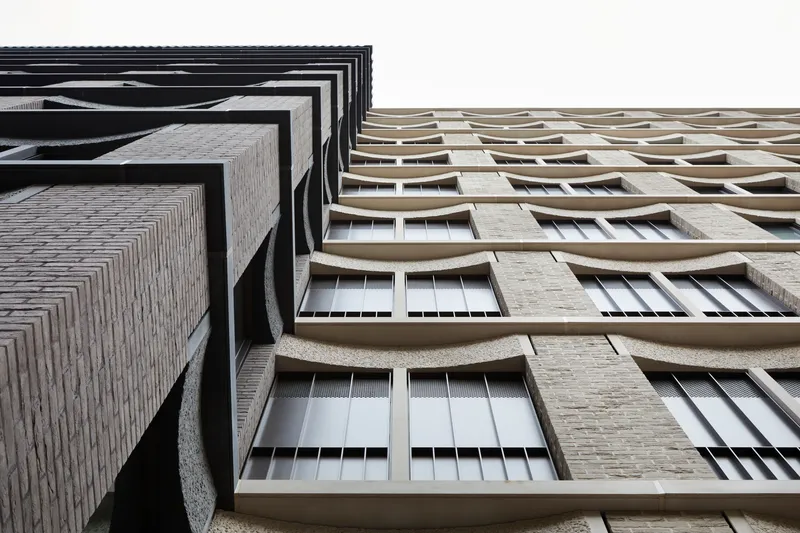 Upward view contrasting a dark stepped corner against curved concrete balcony parapets