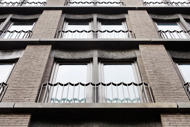 Facade detail showing scalloped metal awnings above windows with textured brick piers