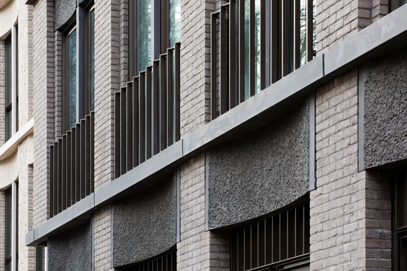 Facade composition mixing textured brick panels, black metal fins and smooth concrete slabs