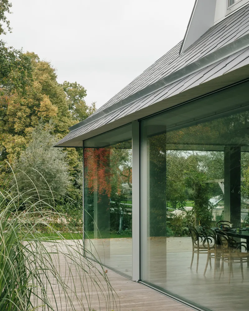 Corner of the glass extension with ornamental grasses beside the sliding doors