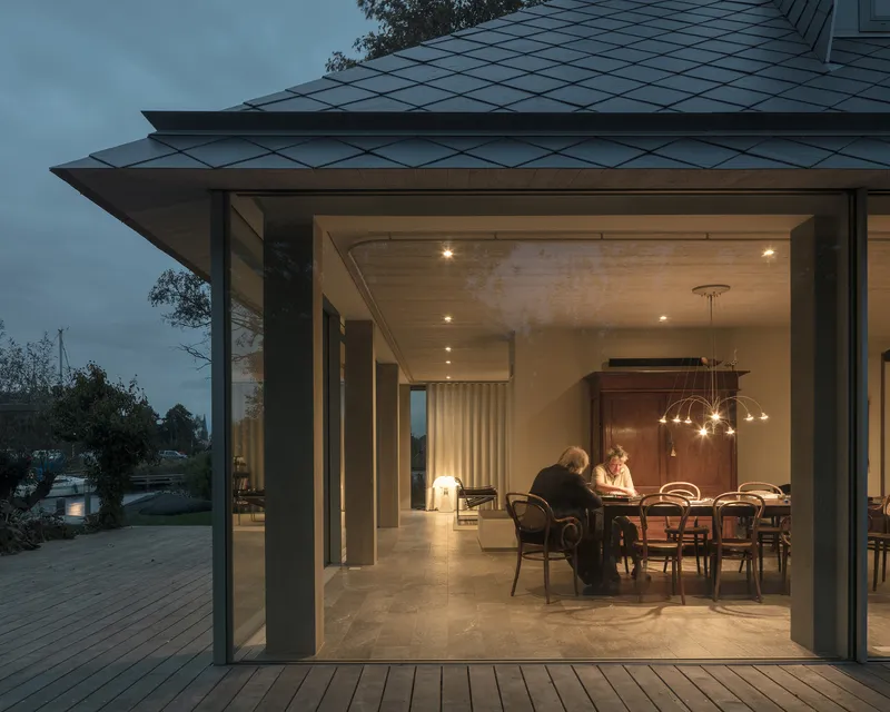 Open glass doors framing a dining room with pendant lighting at dusk