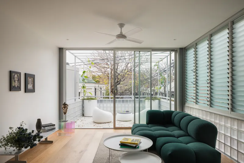 Living room with glass block wall and sliding doors opening to a terrazzo courtyard