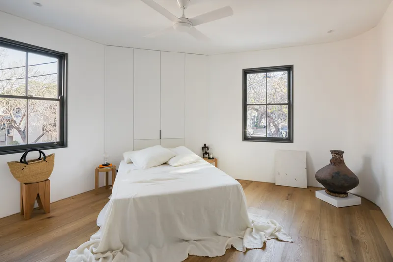 Bedroom with tall built-in wardrobe and black-framed windows overlooking bare winter trees