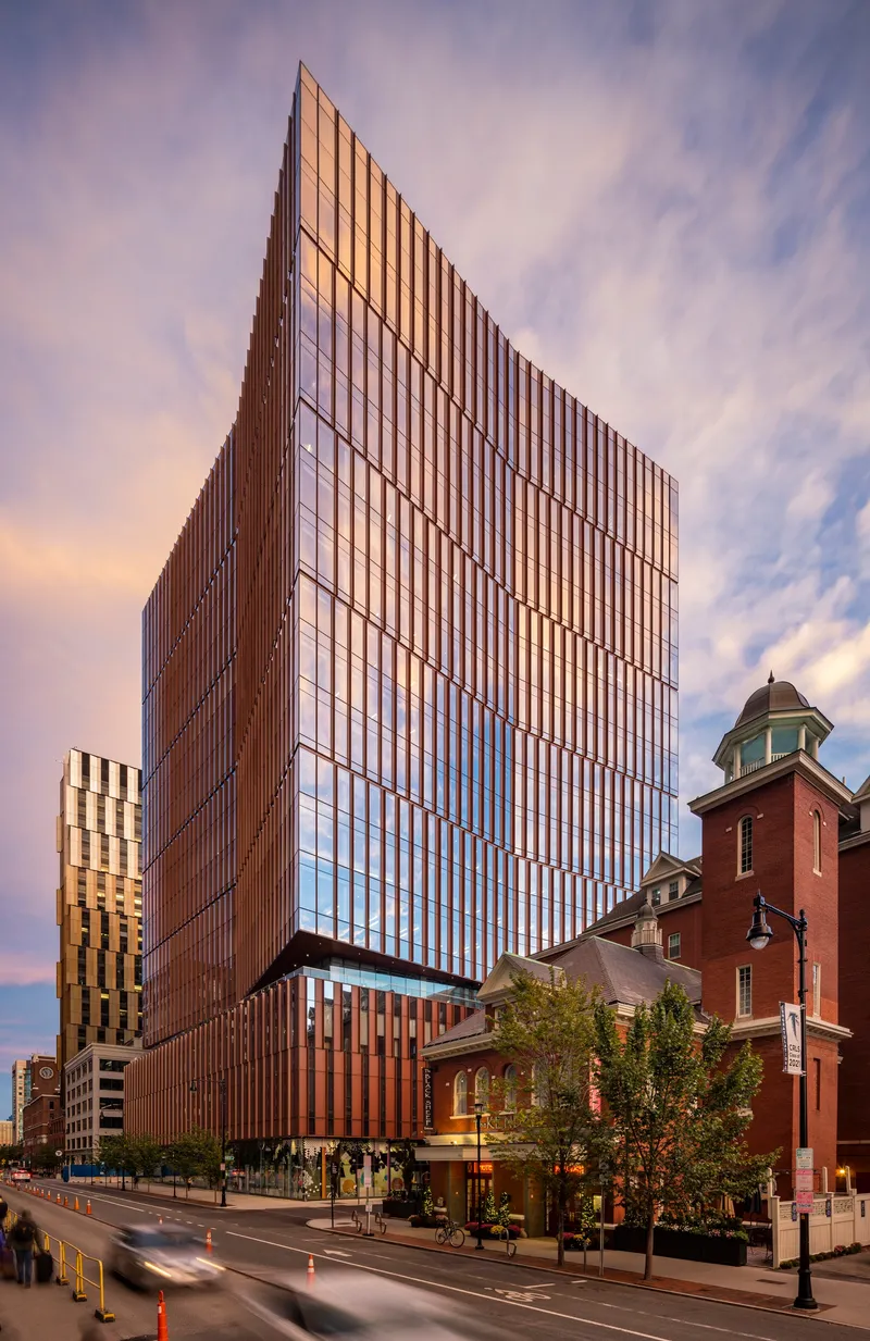 Street view of the tower at sunset beside a historic red brick building with cupola