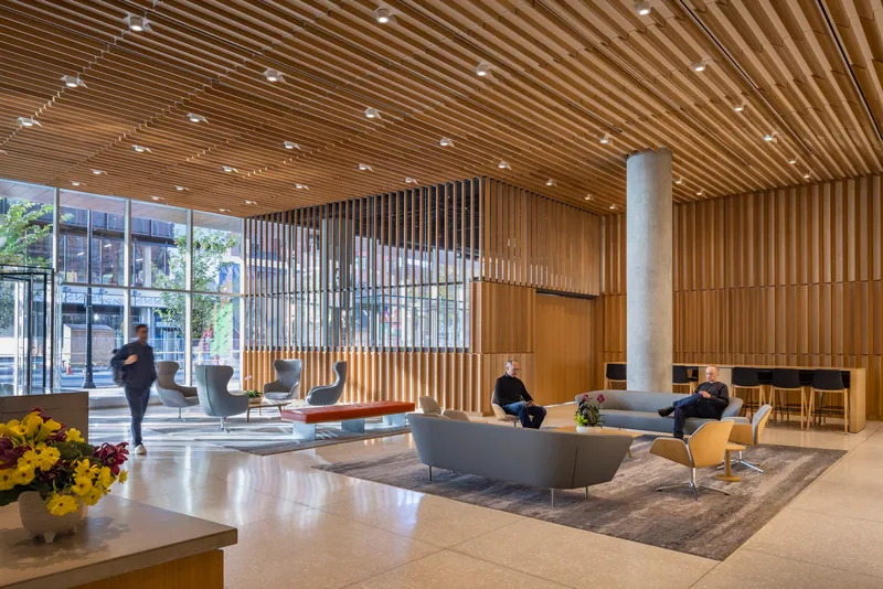 Lobby interior with timber slat ceiling and vertical screen dividing the lounge seating from the glazed street entrance
