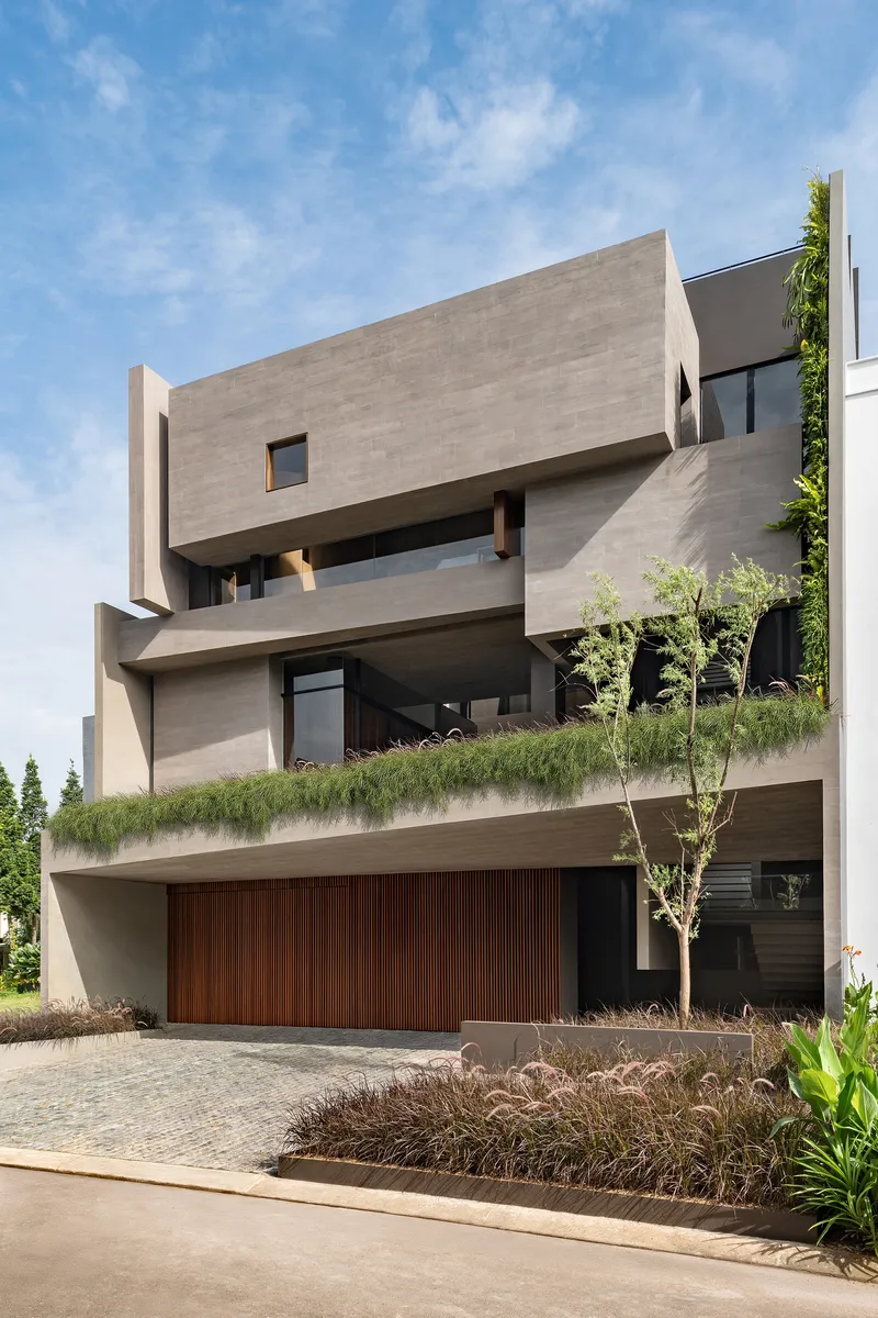 Stacked concrete volumes with planted terraces and vertical garden wall under a blue sky