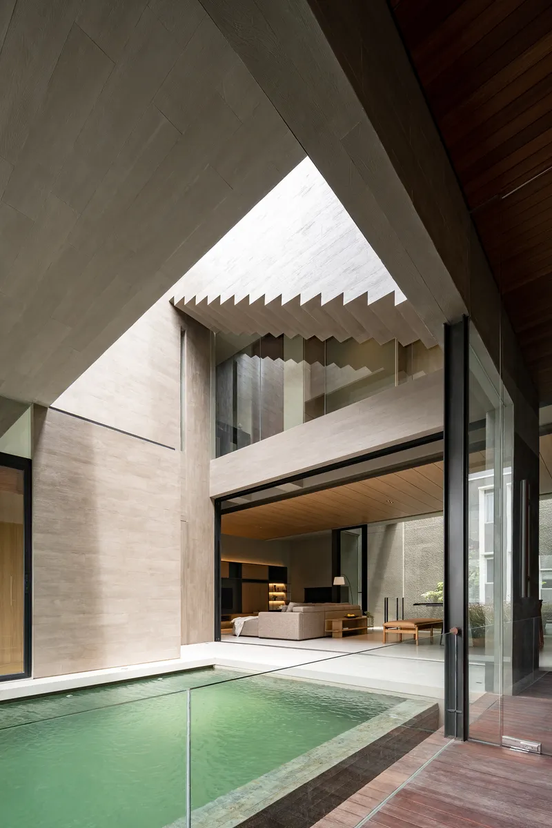 Central courtyard with triangular skylight above floating concrete staircase and shallow pool