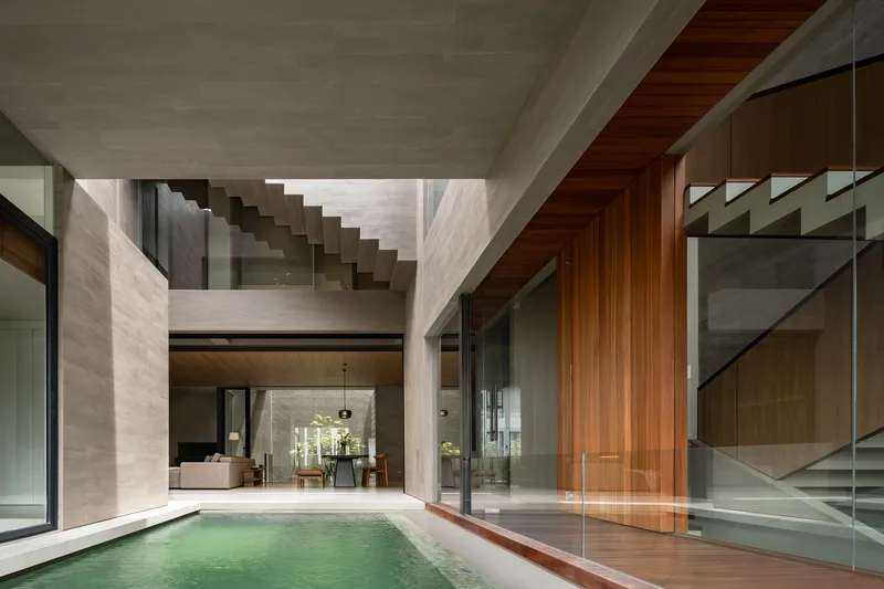 Interior courtyard with narrow lap pool flanked by stone walls and glass doors beneath a timber ceiling