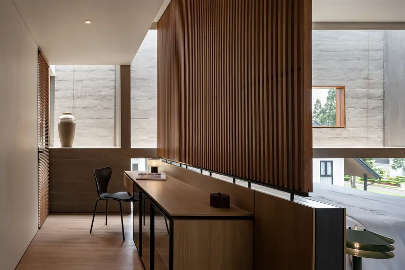 Study area with vertical timber slat screen and desk facing stone walls with clerestory windows