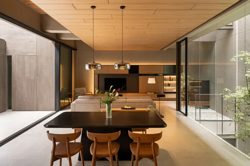 Dining area looking through to a sunken living room with glass-walled courtyards on both sides