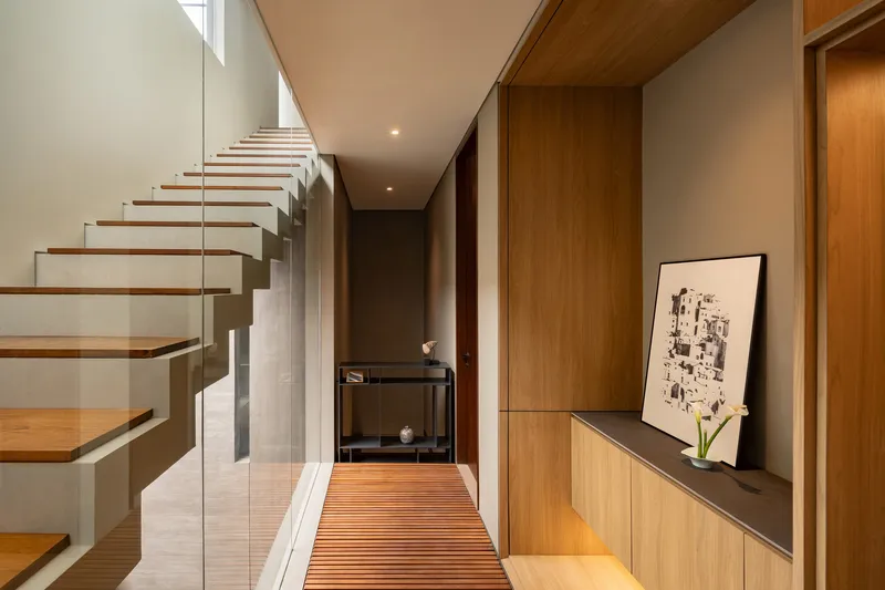 Entry hall with cantilevered timber staircase and slatted wood runner along the built-in cabinet