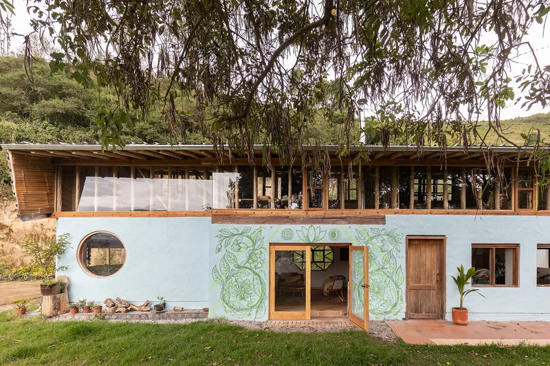 Two-storey facade with painted murals, a circular window, timber-framed upper level, and eucalyptus trees overhead