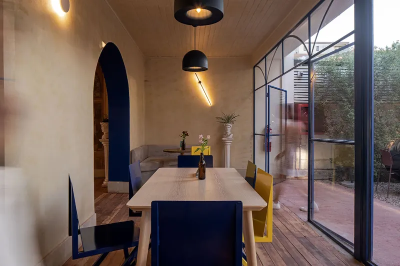 Dining room with timber plank ceiling and blue steel glazed wall overlooking a courtyard