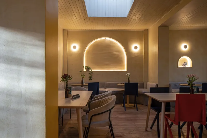 Dining area with timber slat ceiling and backlit arched niche flanked by circular wall lights