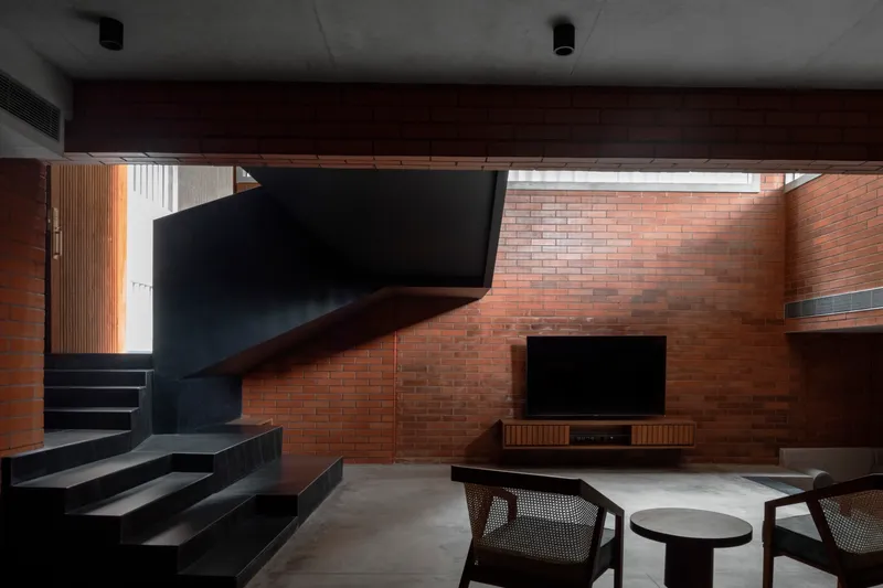 Double-height living room with brick walls, a black steel staircase, and a skylight overhead