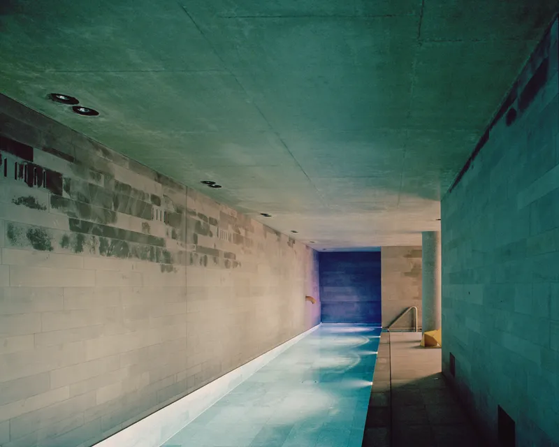 Concrete-lined pool corridor with water surface reflecting color gradation on rear wall