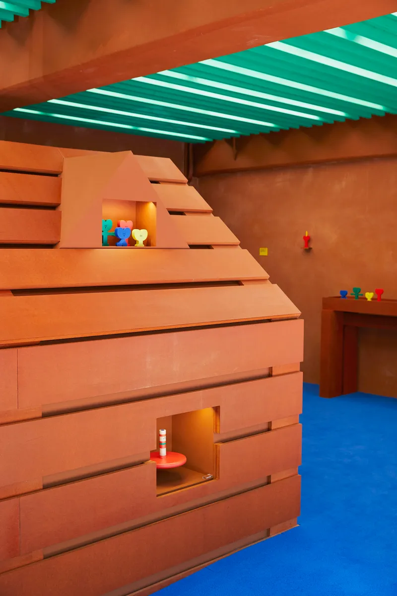 Corner view of stepped timber structure with square openings and colorful toys on shelves