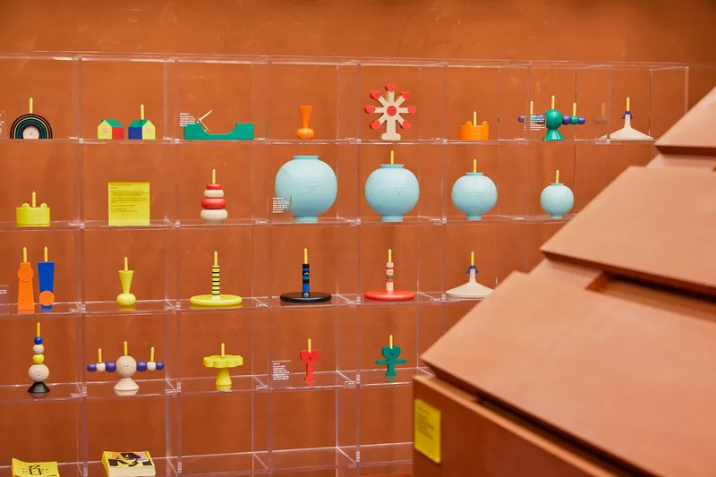 Clear acrylic display shelves holding colorful spinning tops against warm terracotta walls