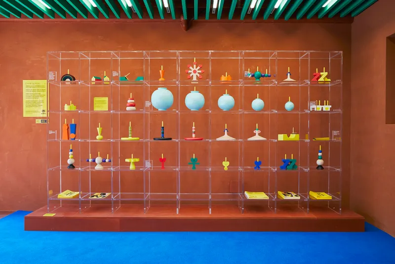 Grid of transparent shelving units displaying toy collection beneath green linear ceiling lights