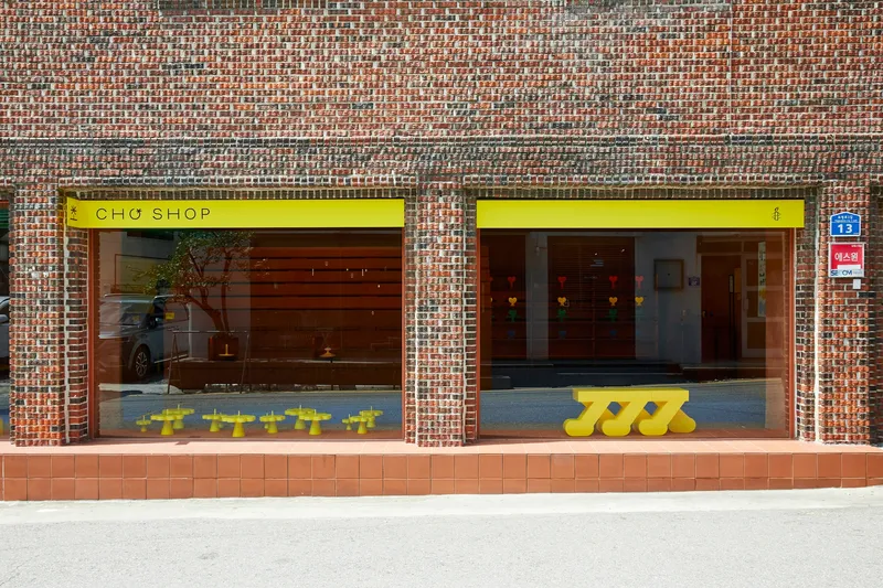 Street facade with patterned brickwork and full-height glazing beneath yellow signage bands