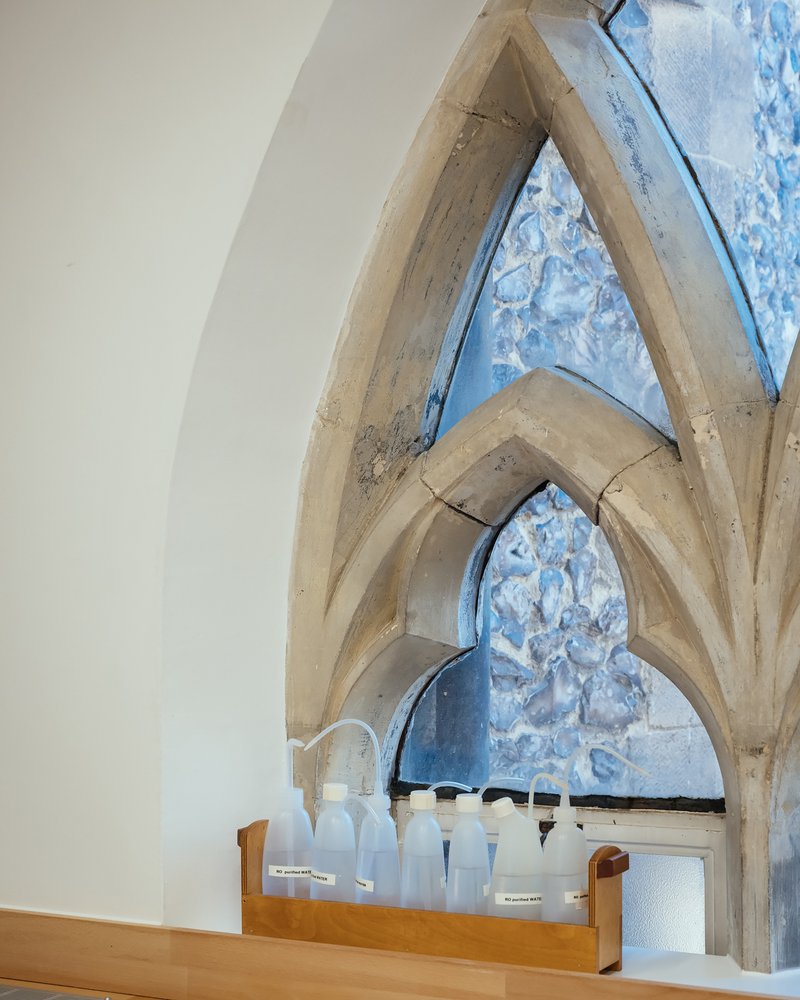 Detail of pointed arch timber beams framing marbled blue paint on restored masonry