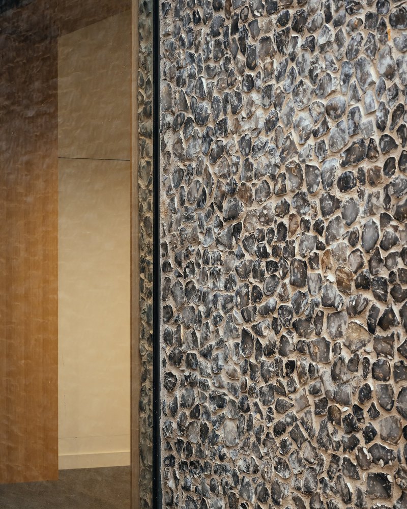 Detail of cobblestone wall meeting smooth limestone panels with a metal trim separating the two textures