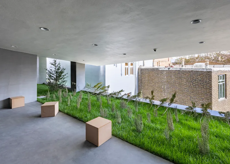 Gallery space with planted slope and cube benches beneath concrete ceiling and clerestory windows