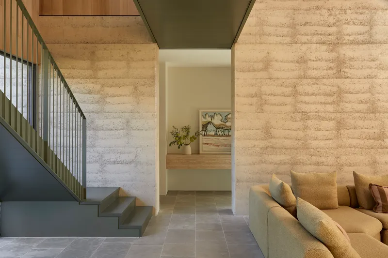 Interior view of folded steel staircase rising between board-marked concrete walls
