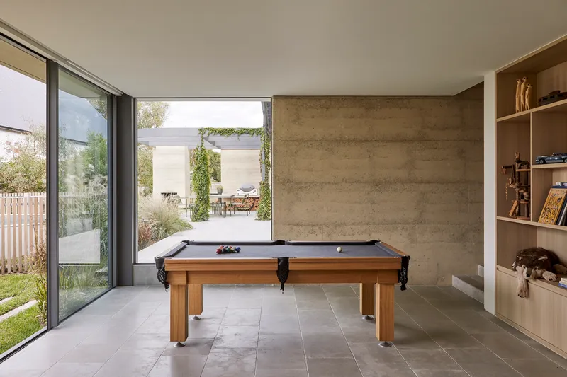 Games room with billiards table looking through sliding glass doors to planted courtyard beyond