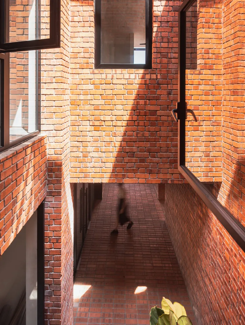 Brick courtyard seen from above with warm sunlight casting shadows of people walking below
