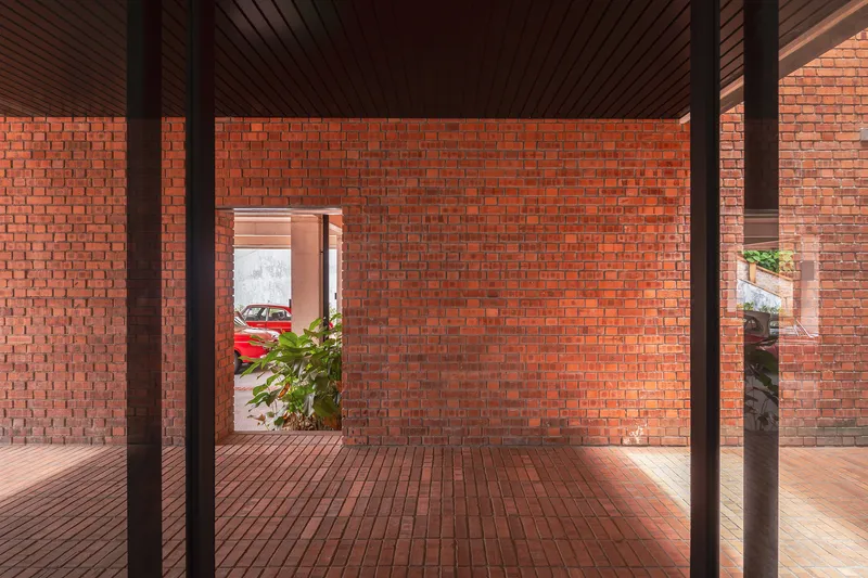 Interior room with exposed timber columns and slatted ceiling looking through framed brick opening to street