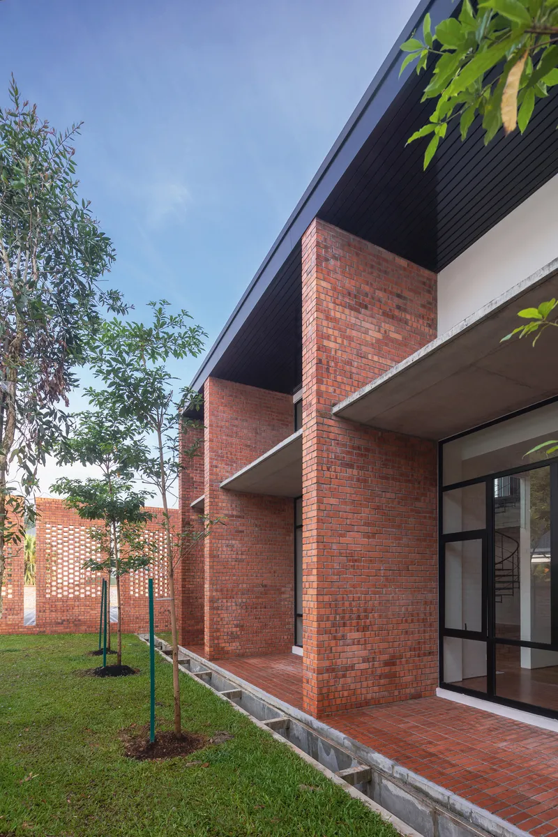 Exterior courtyard with red brick walls and projecting balconies under black soffits near planted lawn