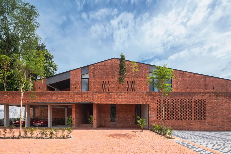 Brick facade with perforated ventilation panels and recessed carport under cloudy afternoon sky