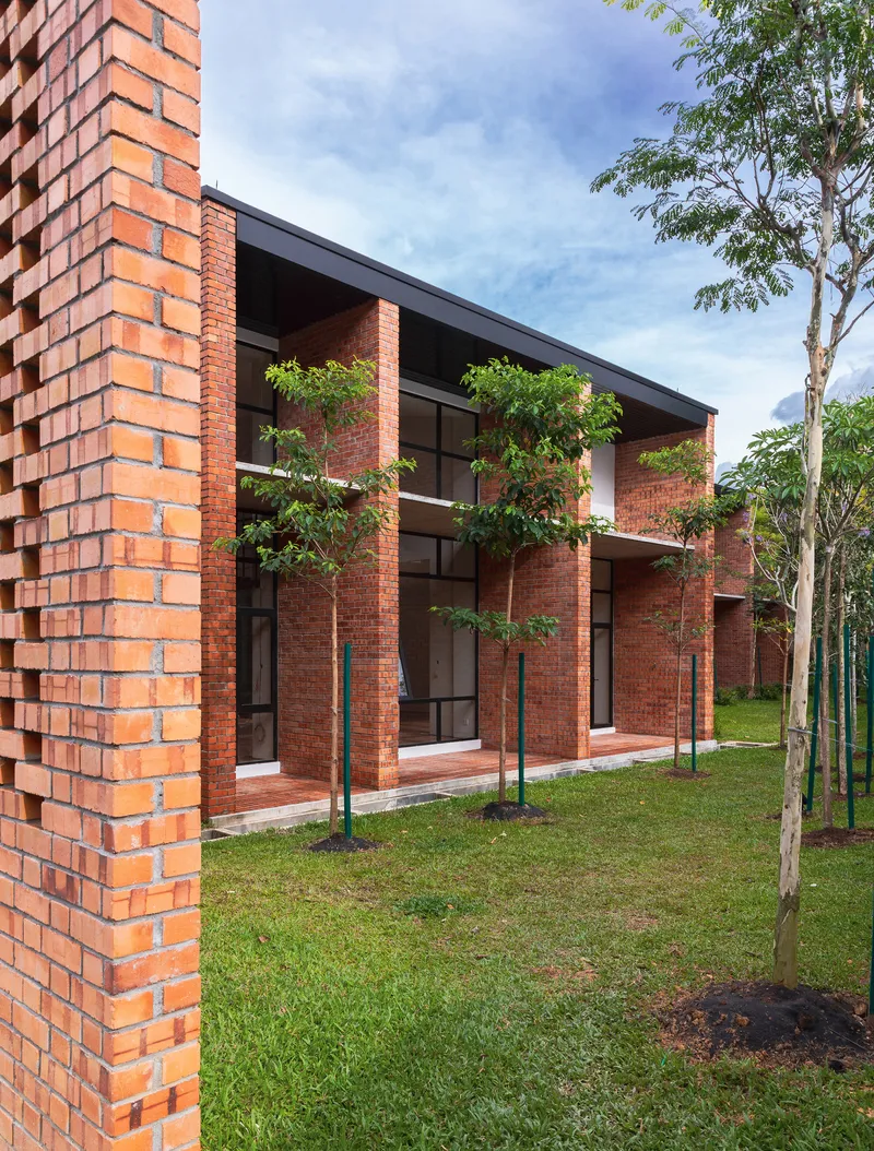 Side view of brick facade with deep overhangs and glazed openings facing a grassed lawn