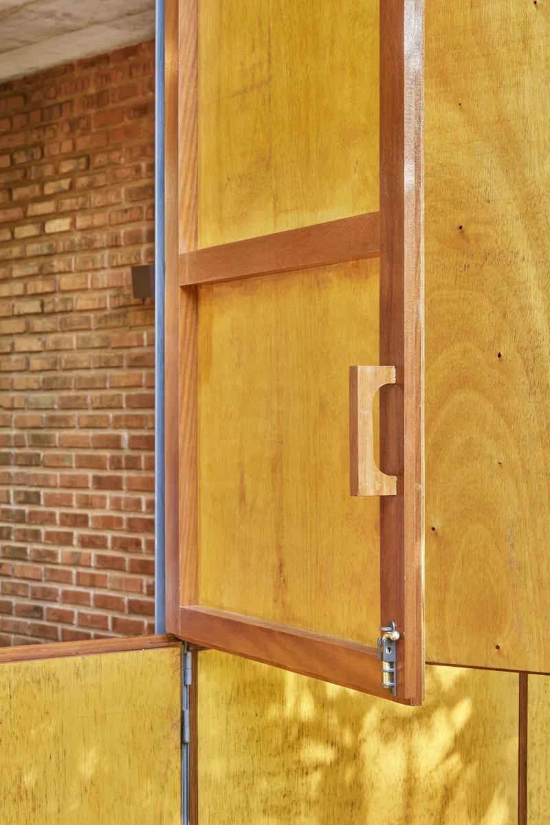 Detail of timber door handle and metal latch against yellow paneled surface
