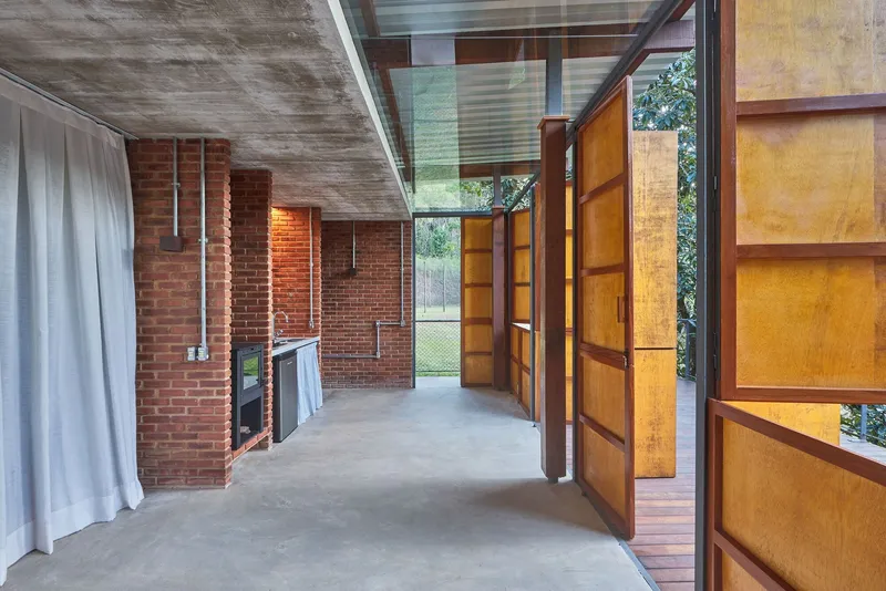Concrete floor interior with brick columns and open timber doors leading to deck