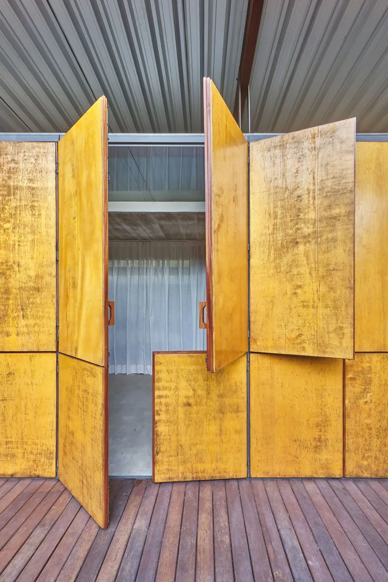 Central plywood doors swung open showing interior space and ribbed metal ceiling above timber deck