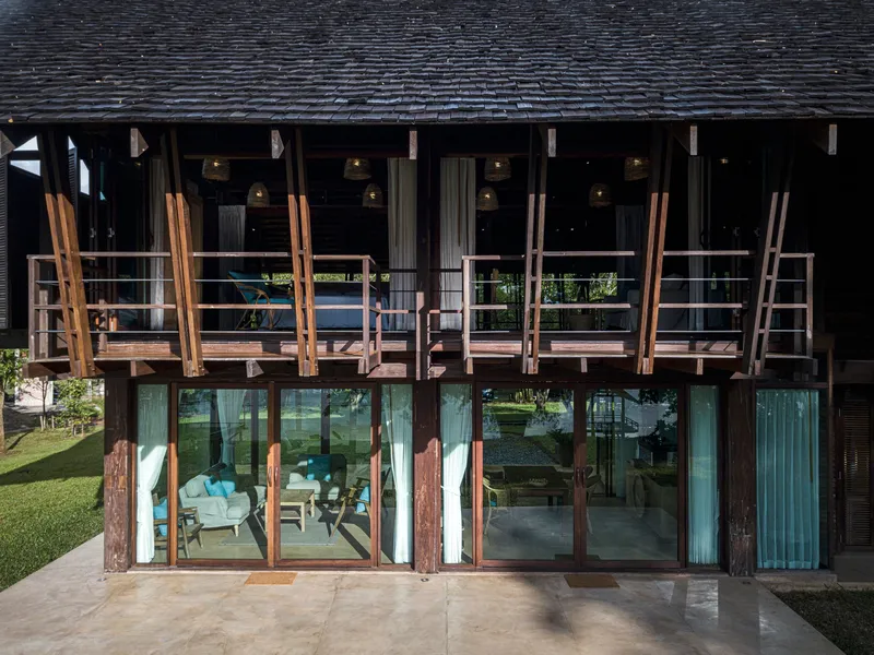 Facade with horizontal timber slat shutters above full-height glazing reflecting the surrounding lawn