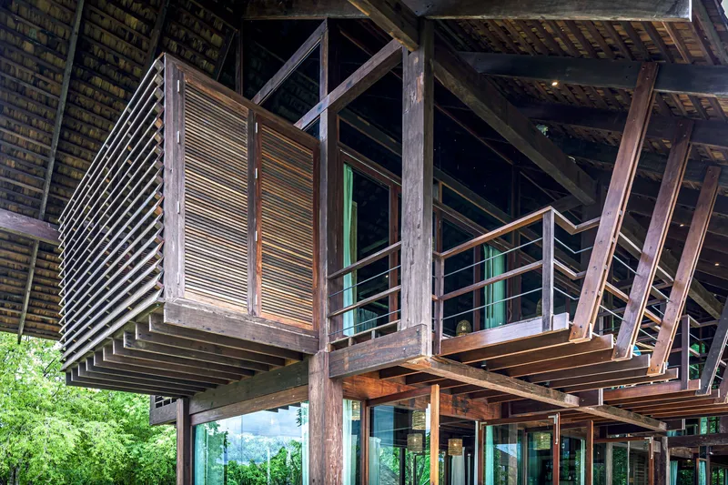 Underside view of cantilevered timber balcony with horizontal slat screens and exposed structural beams