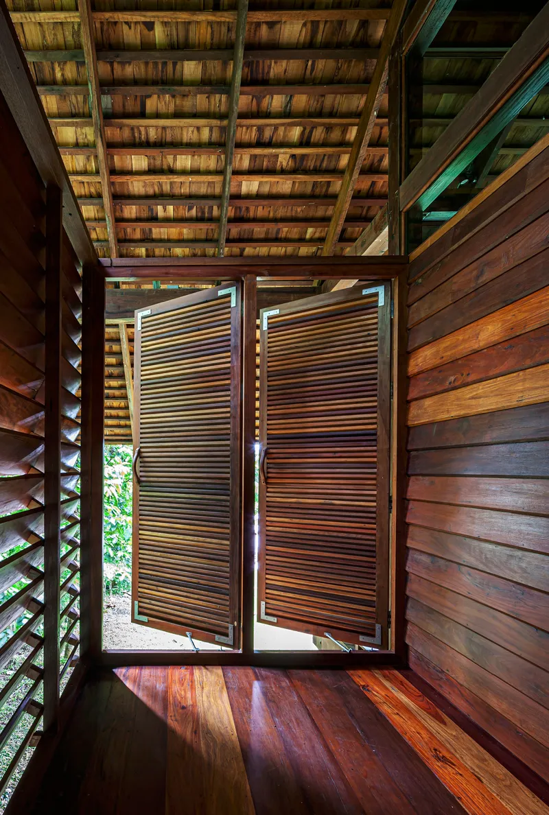 Timber hallway with horizontal slat shutters opening outward under a tiled pitched roof