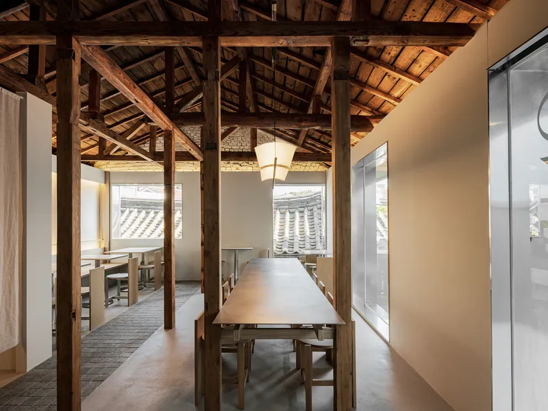 Interior dining space with exposed timber roof trusses and windows framing a curved tile roof