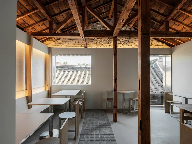 Seating area with timber columns, original roof structure, and windows to neighboring tile roofs