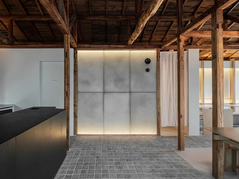 Backlit translucent wall panels with concealed cove lighting surrounded by preserved timber posts and grey brick flooring