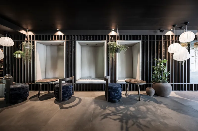 Interior seating area with three illuminated niches, vertical slat dividers, and hanging spherical pendant lights